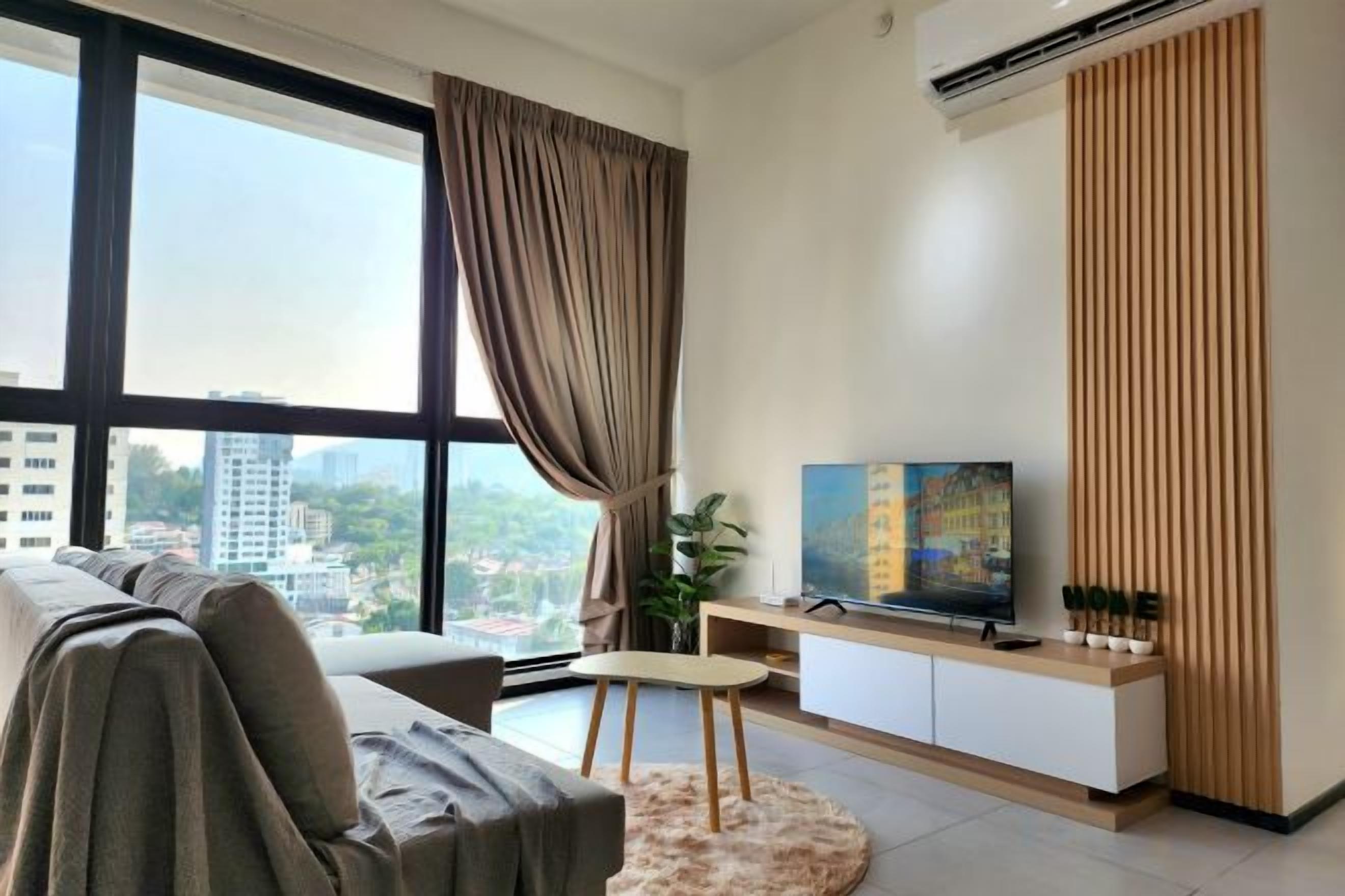 A modern living room with a sofa, a television, and a city view through large windows.