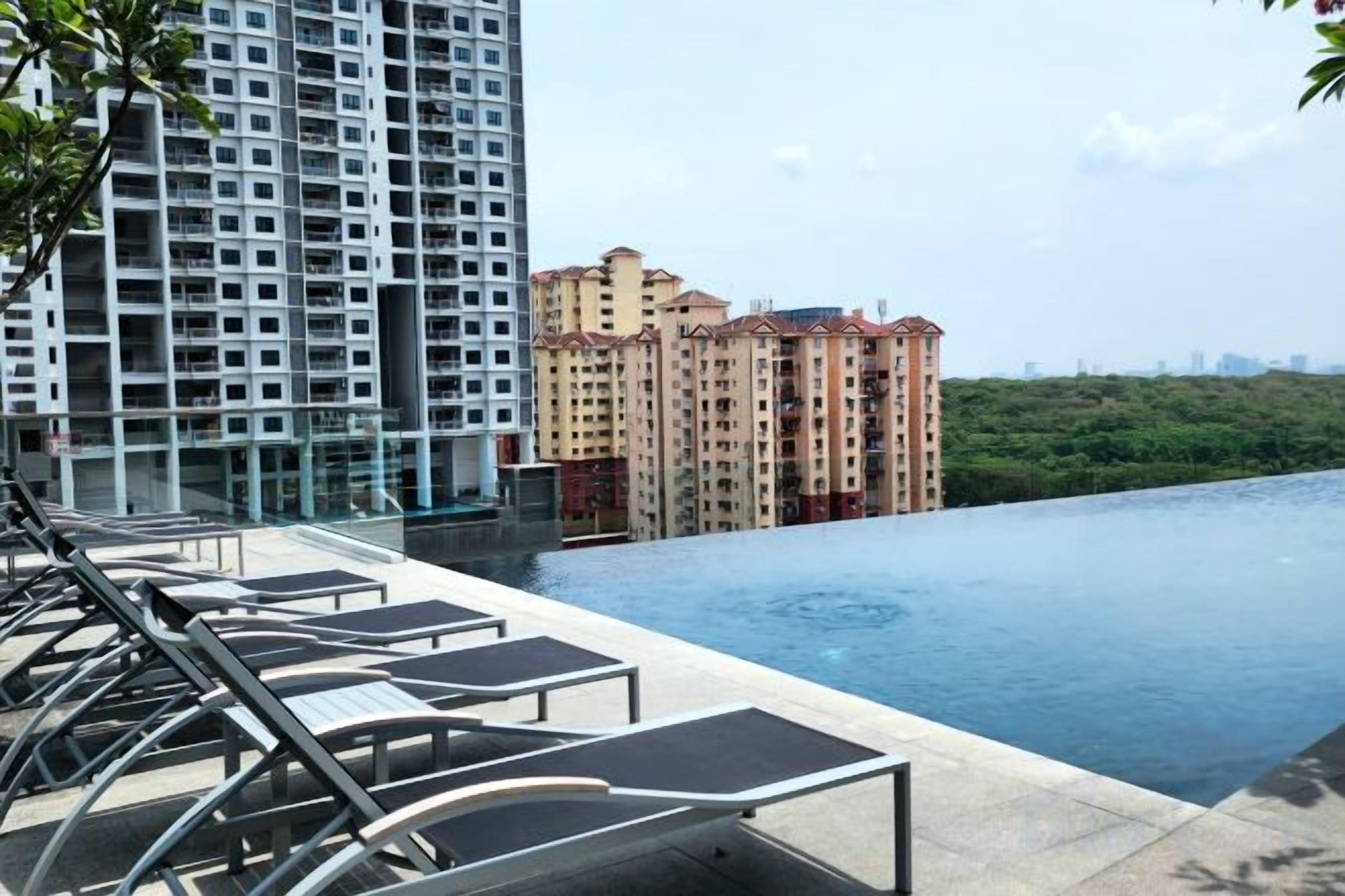 A rooftop pool with lounge chairs, a view of high-rise buildings, and a clear sky.