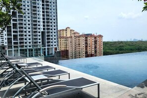 A rooftop pool with lounge chairs, a view of high-rise buildings, and a clear sky. - Urban Muji Retreat Suites (George Town)