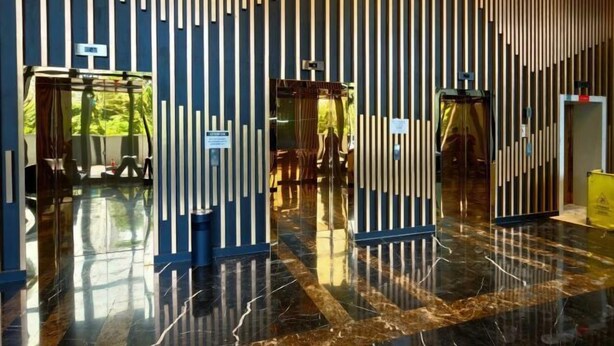 A modern lobby with vertical wooden slats, a marble floor, and glass doors leading to a seating area. - Urban Muji Retreat Suites (George Town)