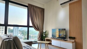 A modern living room with a sofa, TV, and city view. - Urban Muji Retreat Suites (George Town)
