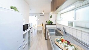 Una cocina moderna con armarios blancos, un microondas y una tabla de madera con verduras.