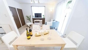 Una sala de estar moderna con una mesa de comedor preparada para cuatro personas, un televisor y un sofá.