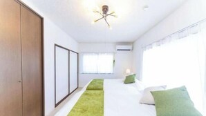Una habitación de hotel con cama, un corredor verde, un armario y una lámpara en el techo.