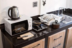 Een keuken met een magnetron, waterkoker en een afdruiprek.