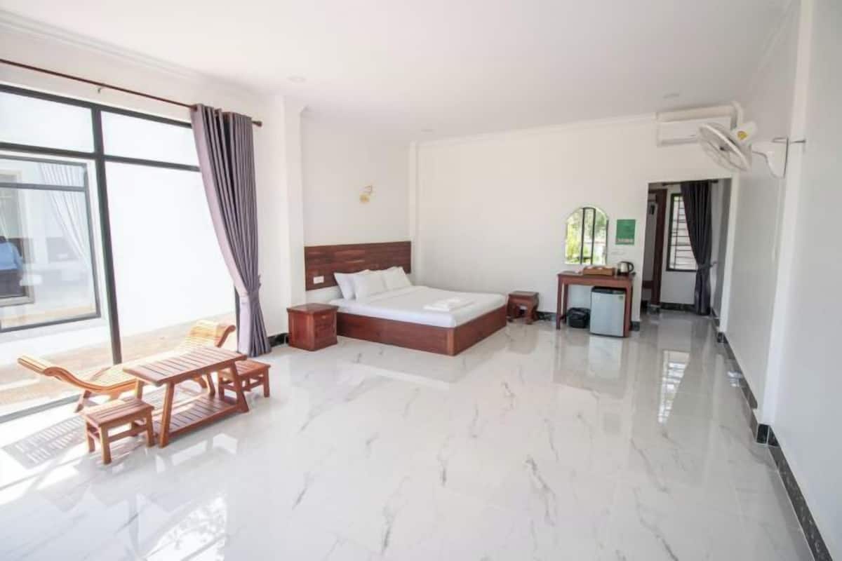 A hotel room with a bed, a desk, a chair, a small table, and a window.