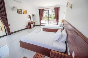 Une chambre d’hôtel avec deux lits, un bureau et une grande fenêtre avec des rideaux.