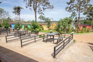 Een terras met tafels en banken, omringd door bomen en gebouwen met kleurrijke gevels.
