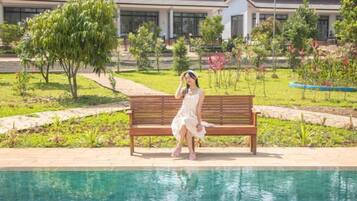 A person sitting on a bench by a pool with a building in the background.