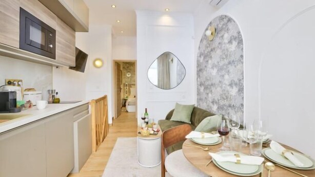 A modern kitchen with a wooden countertop, a microwave, and a dining area with a table set for two. - New! Le Vénitien, Escapade Parisienne, Sacré-Cœur (Paris)