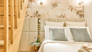 A hotel room with a bed, a nightstand, and a wall with palm tree wallpaper. - New! Le Vénitien, Escapade Parisienne, Sacré-Cœur (Paris)