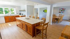 Une cuisine spacieuse dotée de meubles en bois, d’un grand îlot central et d’un coin repas avec des chaises et une table en bois.