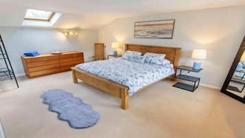 Une chambre à coucher comprenant un lit, une commode, une table de chevet, une lampe et une lucarne.