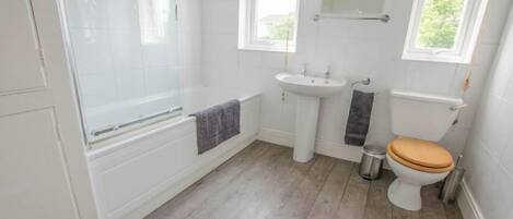 Un baño con bañera, lavabo, inodoro y ventana.