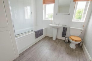 Un baño con bañera, lavabo, inodoro y ventana.