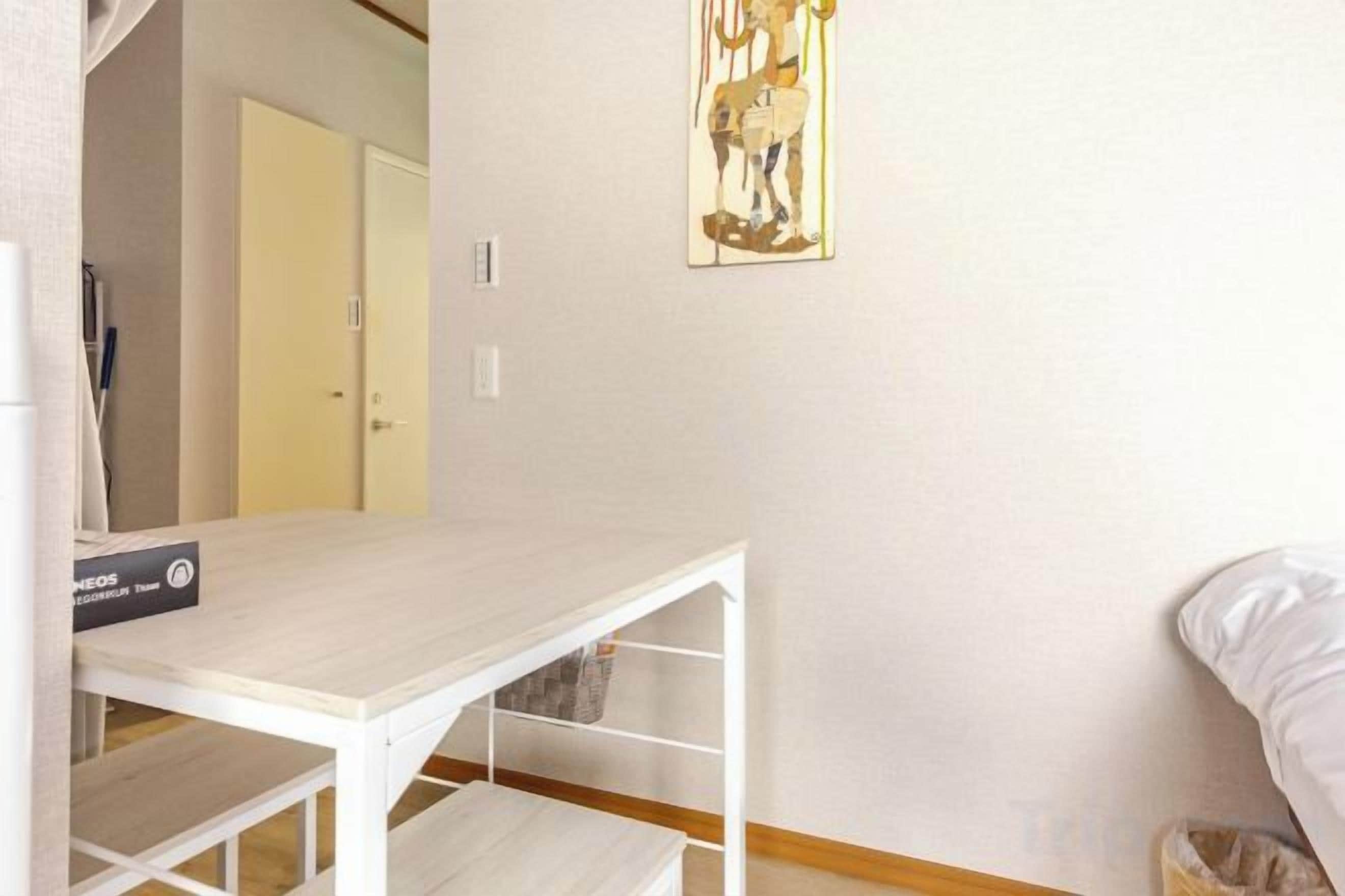 A room with a white table, a bed, and a door in the background.