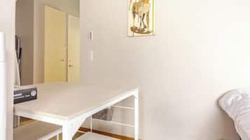 A room with a white table, a bed, and a door in the background.