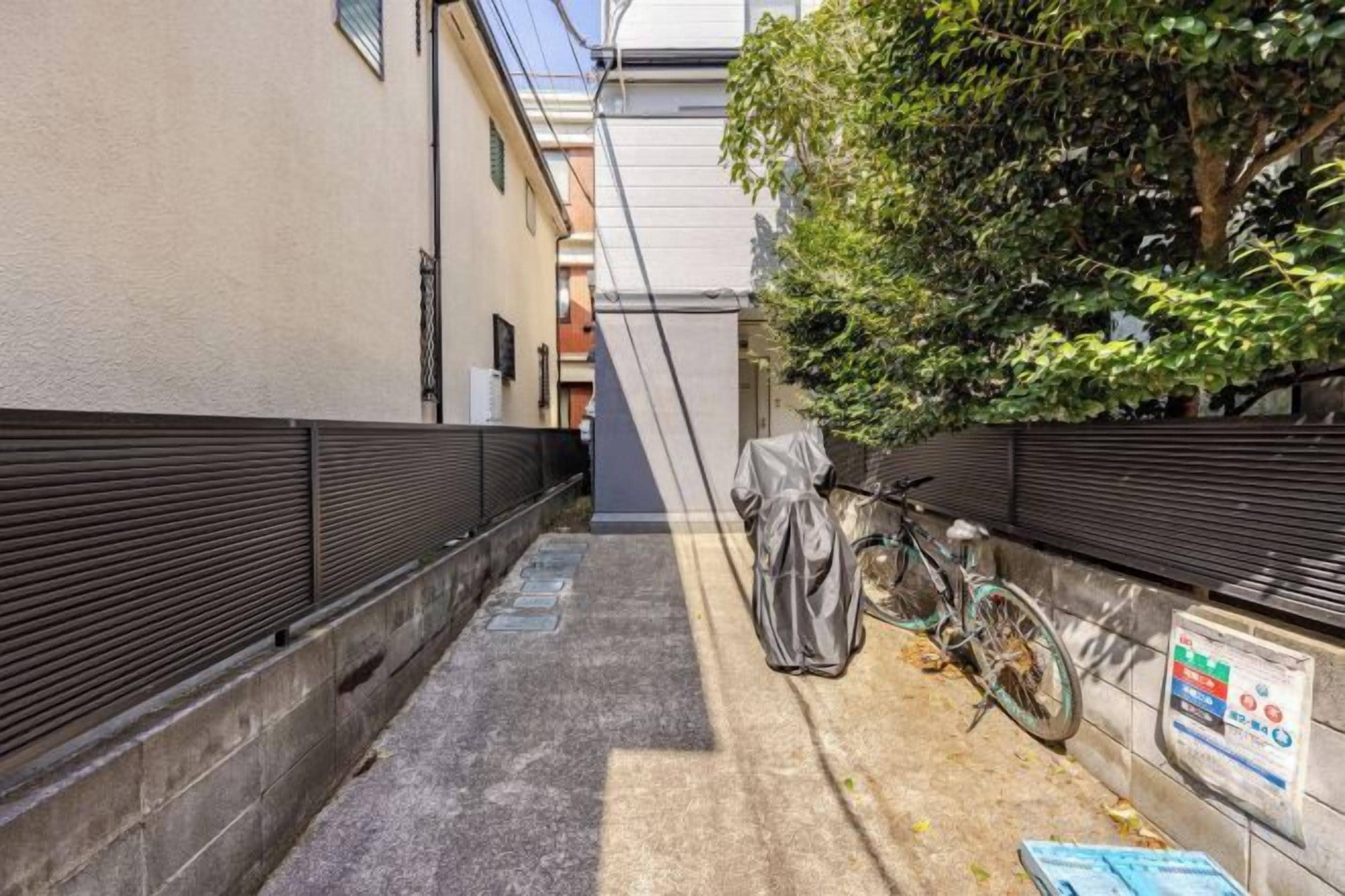 A narrow alleyway with a bicycle leaning against a wall, a covered object, and a sign on the wall.