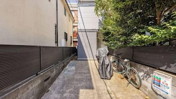 A narrow alleyway with a bicycle leaning against a wall, a covered object, and a sign on the wall.