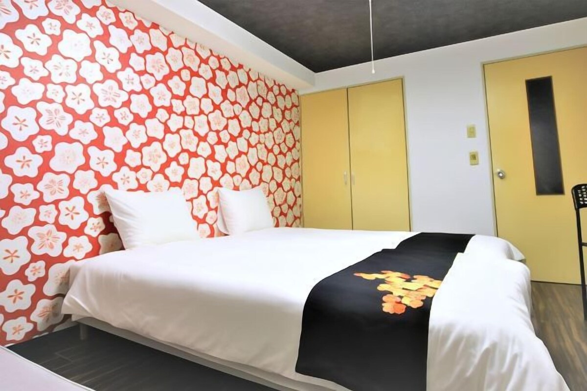 A hotel room with a bed, a yellow door, and a patterned wall.