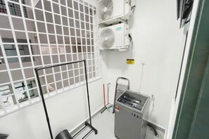 Quarto com janela, aparelhos de ar condicionado, radiador e tomada.