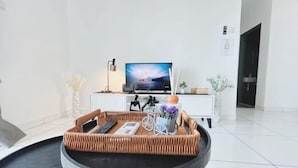 A modern hotel room with a television, a wicker tray table with remote controls, a vase with flowers, and a white console table. - PLATINO Kids Friendly, 3BR Family Suite, Next to Paradigm Mall Escape JB (Tebrau)