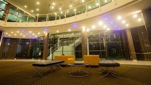 A spacious lobby with a curved ceiling, a staircase, and seating areas.