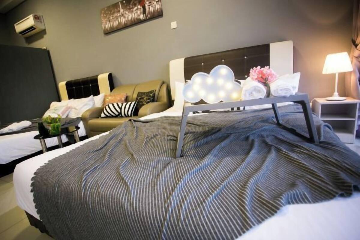 Ein Hotelzimmer mit Bett, Sofa, Nachttisch mit Lampe und Wandklimaanlage.
