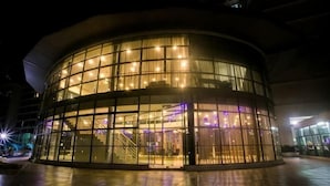 A modern building with a curved glass facade, large windows, and a central staircase.