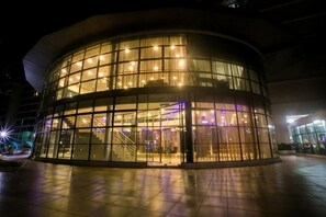 A modern building with a curved glass facade, large windows, and a central staircase. - Palazio Residence By The One - Mount Austin (Tebrau)