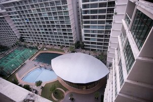 A high-rise building with a swimming pool and a distinctive circular building with a dome-like roof.