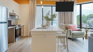 Une cuisine moderne dotée d’un îlot central, d’un coin repas avec un canapé et des chaises, et d’une grande fenêtre offrant une vue dégagée.
