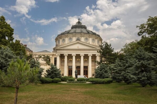 A classical building with a dome and columns, surrounded by a well-maintained lawn and trees. - Rainforest Studio Downtown by Pretty Apartments (Bucharest)
