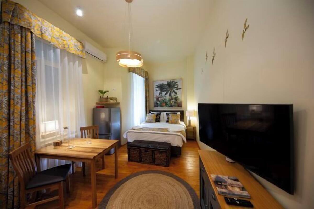 A hotel room with a bed, a TV, a dining table, and a chair.