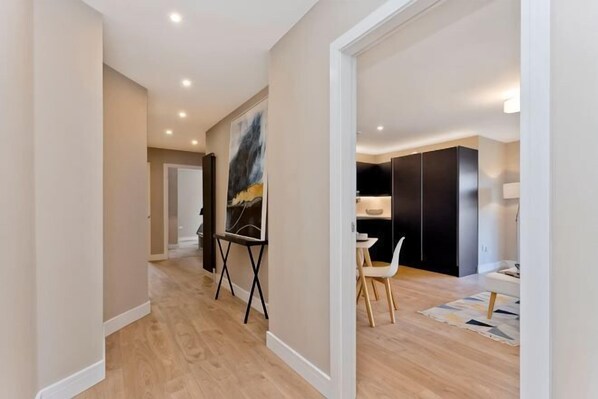 Un intérieur moderne avec un plancher en bois, un coin repas comprenant une table et des chaises, et un grand tableau abstrait accroché au mur.
