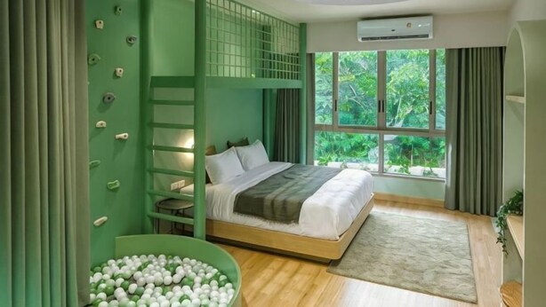 Quarto com beliches, parede de escalada, janela grande e vista para o verde.