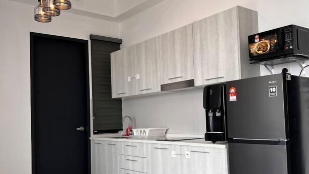 A modern kitchen with white cabinetry, a black refrigerator, and a microwave on the countertop. - Georgetown Urban Suite Family Skypool I SeaView (Jelutong)