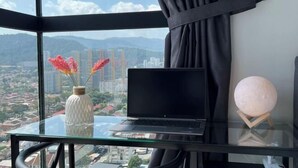 A laptop on a glass table with a vase of flowers and a spherical light fixture. - Georgetown Urban Suite Family Skypool I SeaView (Jelutong)