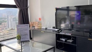 A modern hotel room with a large window, a flat-screen TV, a desk with a computer, and a sign with house rules. - Georgetown Urban Suite Family Skypool I SeaView (Jelutong)