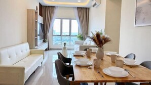 A modern dining area with a wooden table, white plates, and a view through large windows. - Nexus Kajang by Luvit Stay (Kajang)