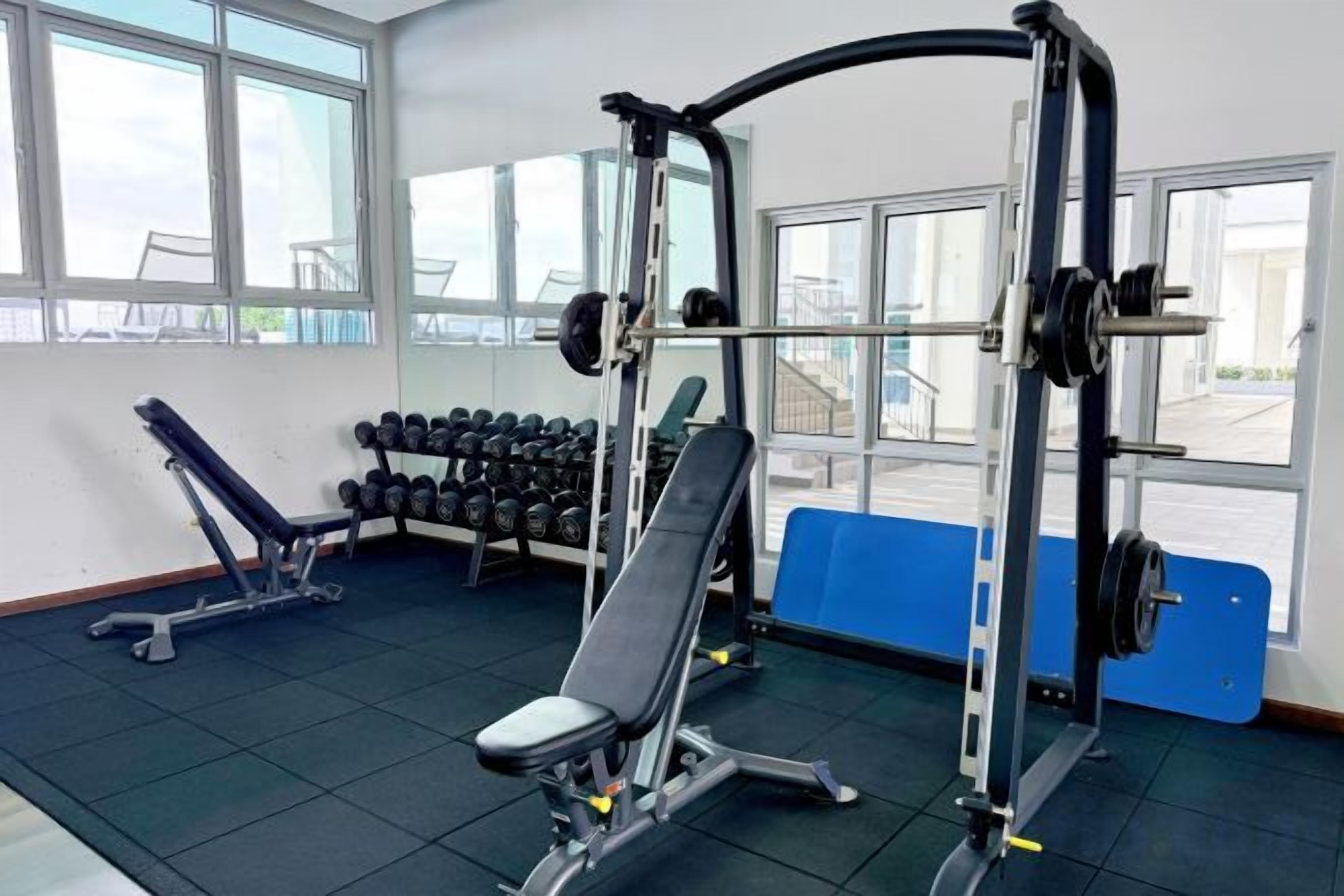 Ein Fitnessstudio mit Gewichten, Hanteln und Bänken.