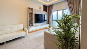 A modern living room with a sofa, TV, ceiling fan, and a large window with curtains. - Nexus Kajang by Luvit Stay (Kajang)