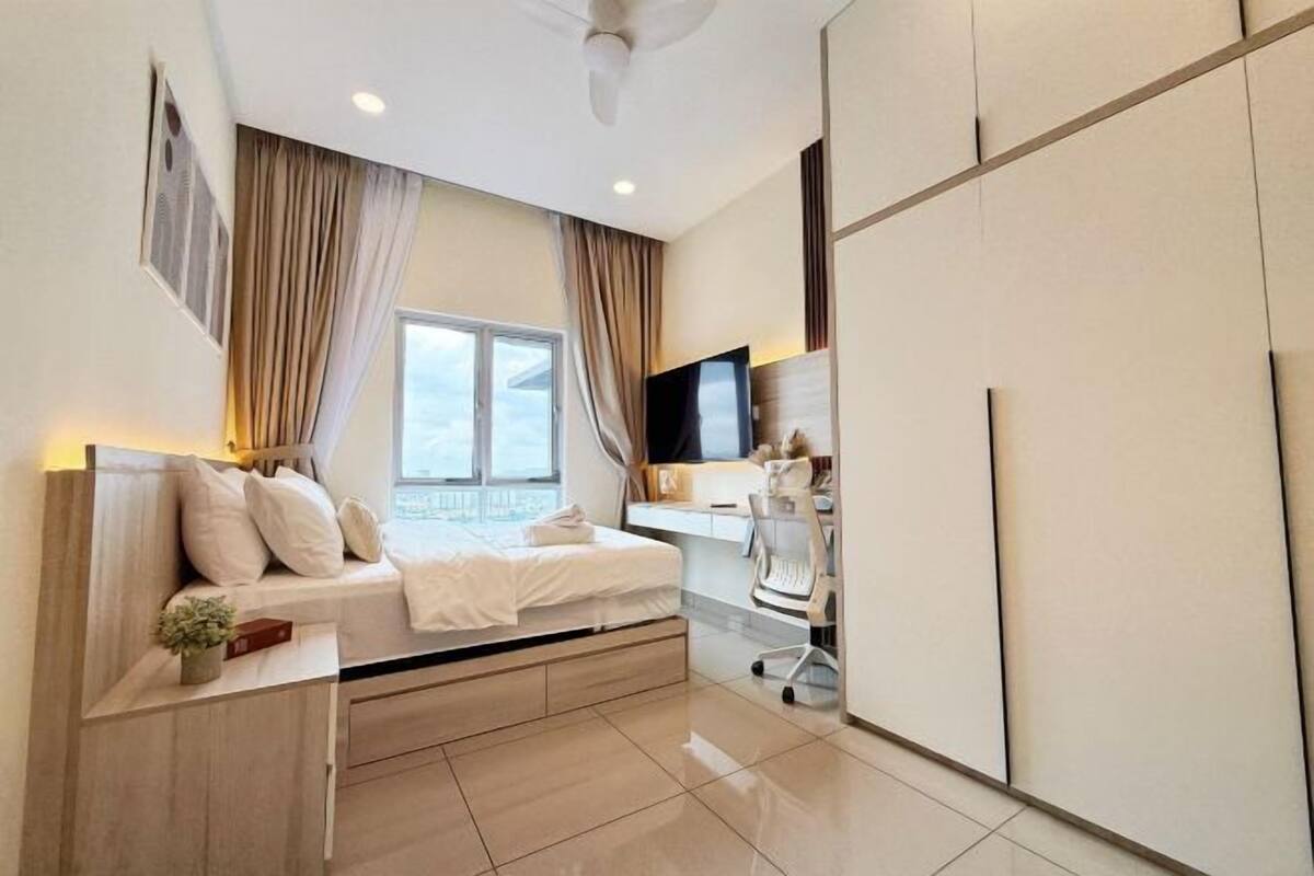Ein modernes Schlafzimmer mit Bett, Schreibtisch und Fernseher.