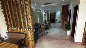 Un hall de hotel con mostrador de recepción, zona de estar y plantas en macetas.