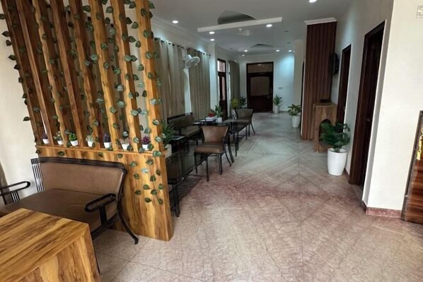 A hotel lobby with a reception desk, seating area, and potted plants. - HOTEL ASHISH (Baddi)