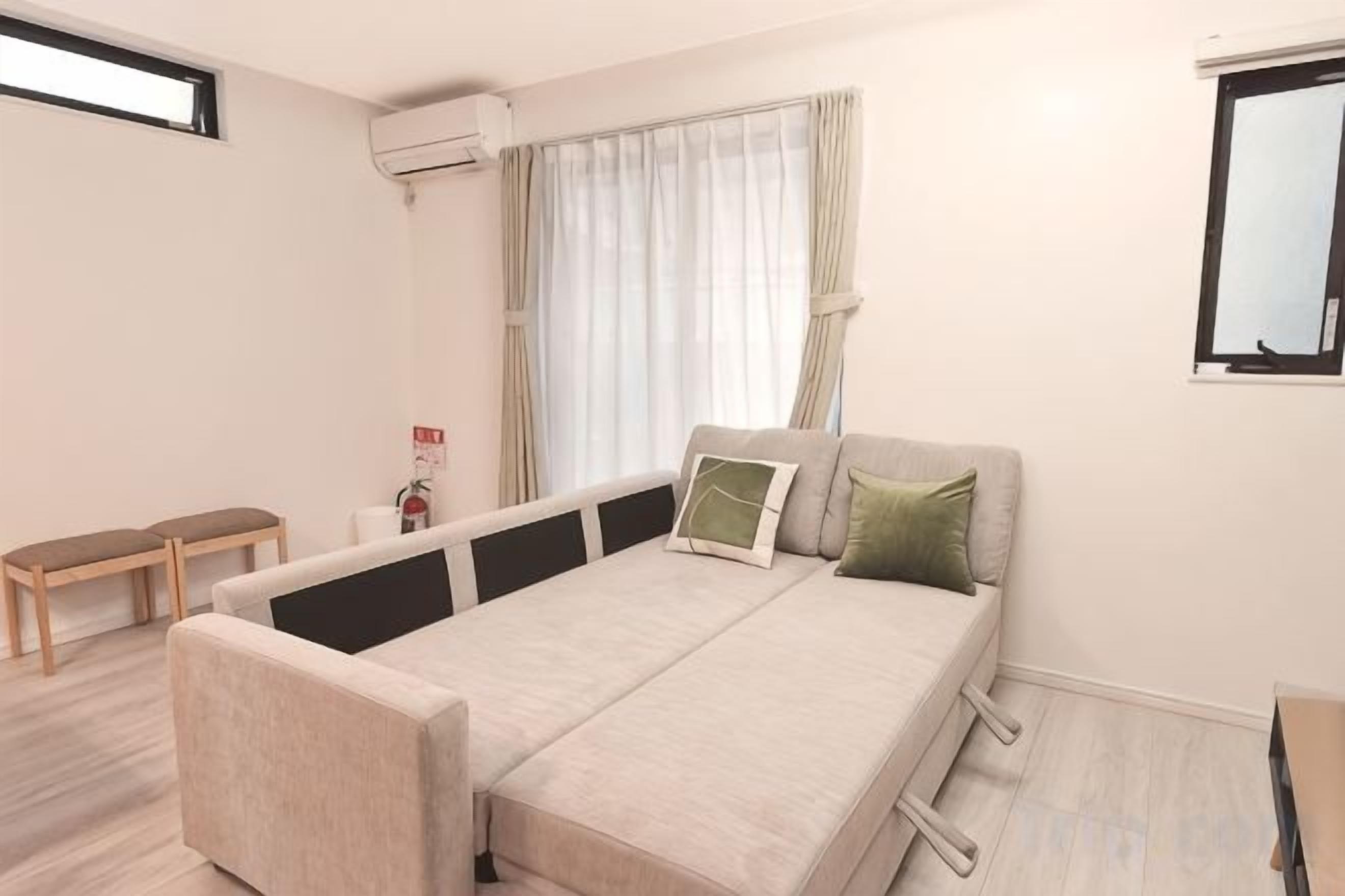 Ein Schlafzimmer mit einem Bett, einer Bank, einem Fenster und einer Klimaanlage.