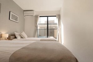 A hotel room with a large bed, a bedside table with a lamp, and a view of a building through a window. - Tsubakirakukyo (Osaka)