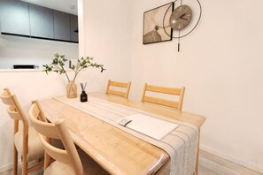 A dining area with a wooden table, chairs, a vase with plants, and a wall clock. - Tsubakirakukyo (Osaka)