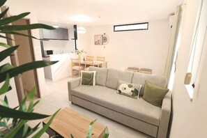 A modern living room with a sofa, a dining table, and a kitchen in the background. - Tsubakirakukyo (Osaka)