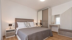 Een moderne slaapkamer met een groot bed, nachtkastjes, een kledingkast en een spiegel.